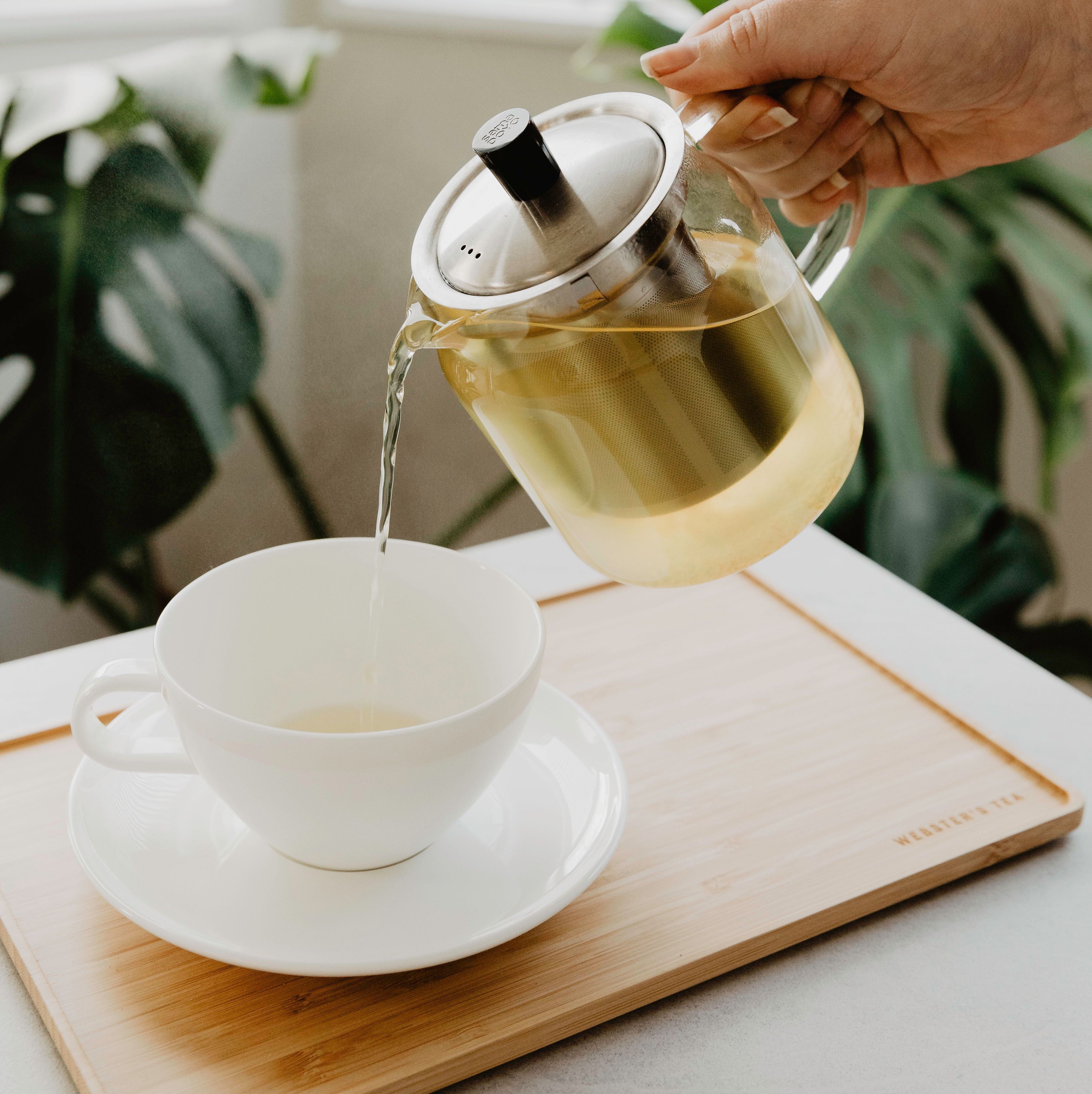 Pouring tea into a mug on a tea tray.